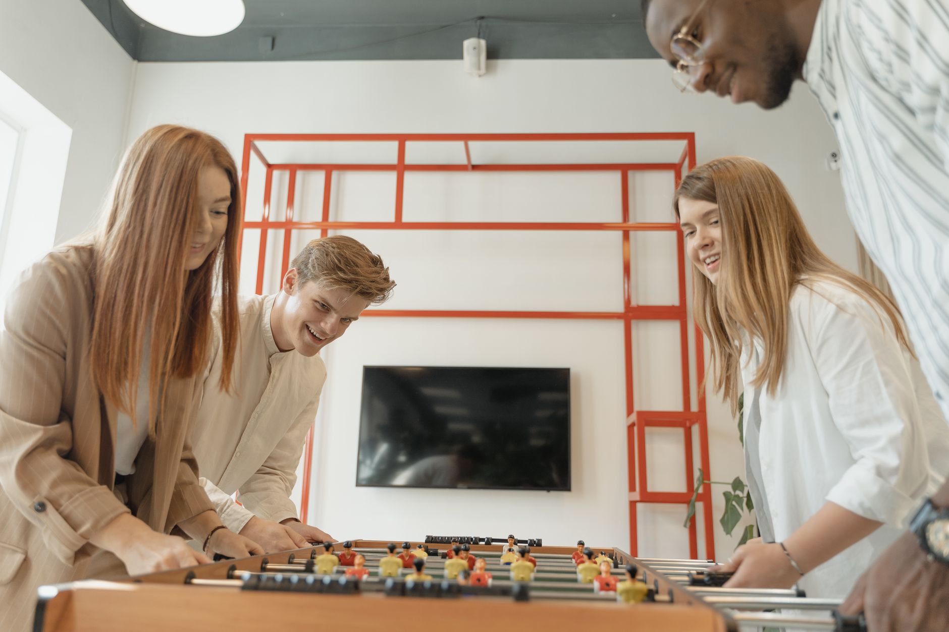 Excited young adults engaged in a fun game of table football indoors.