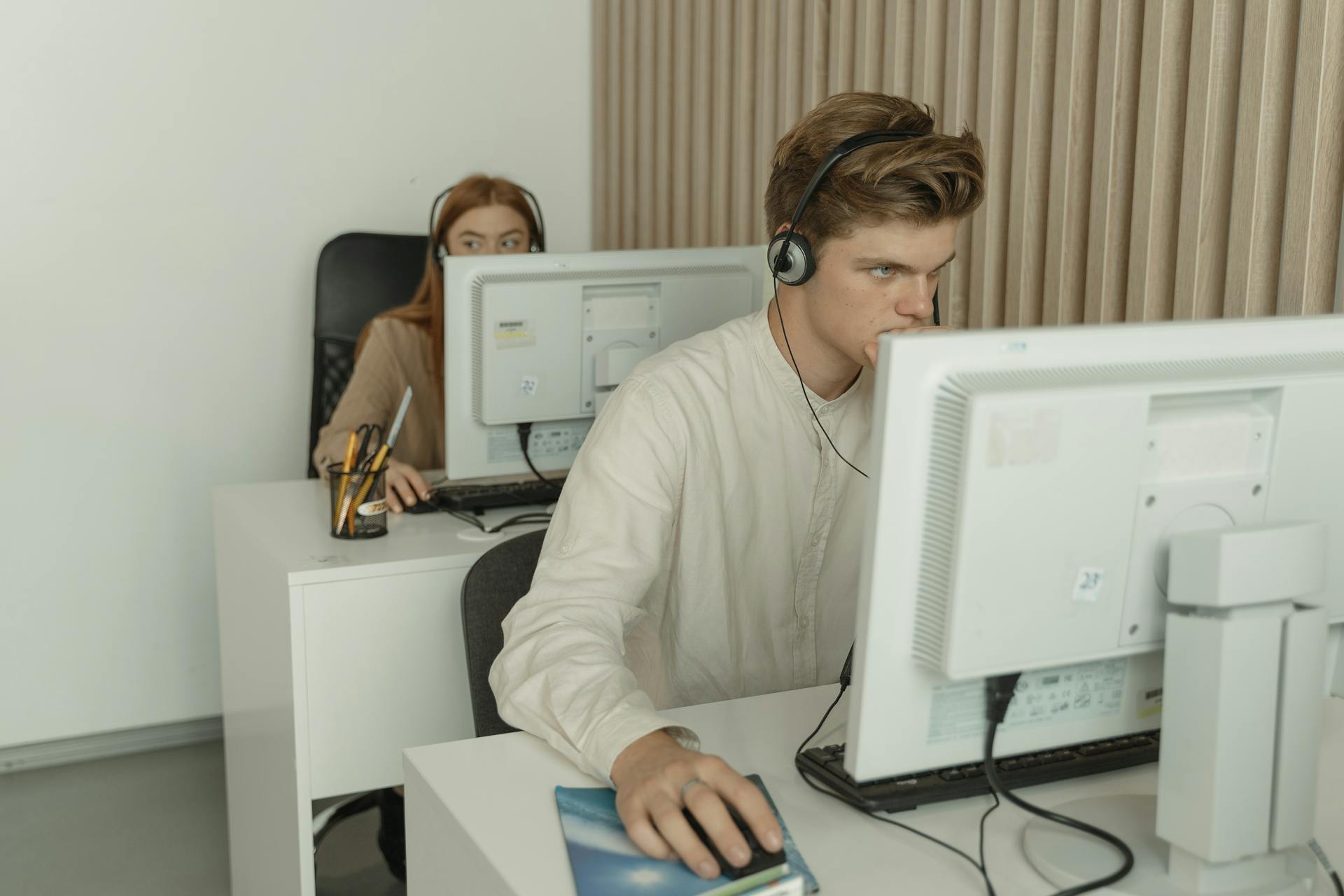 Two young professionals working diligently on computers in a modern office setting.