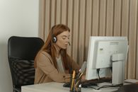 在办公室环境中，一位戴着耳机的女员工正在台式电脑前工作
