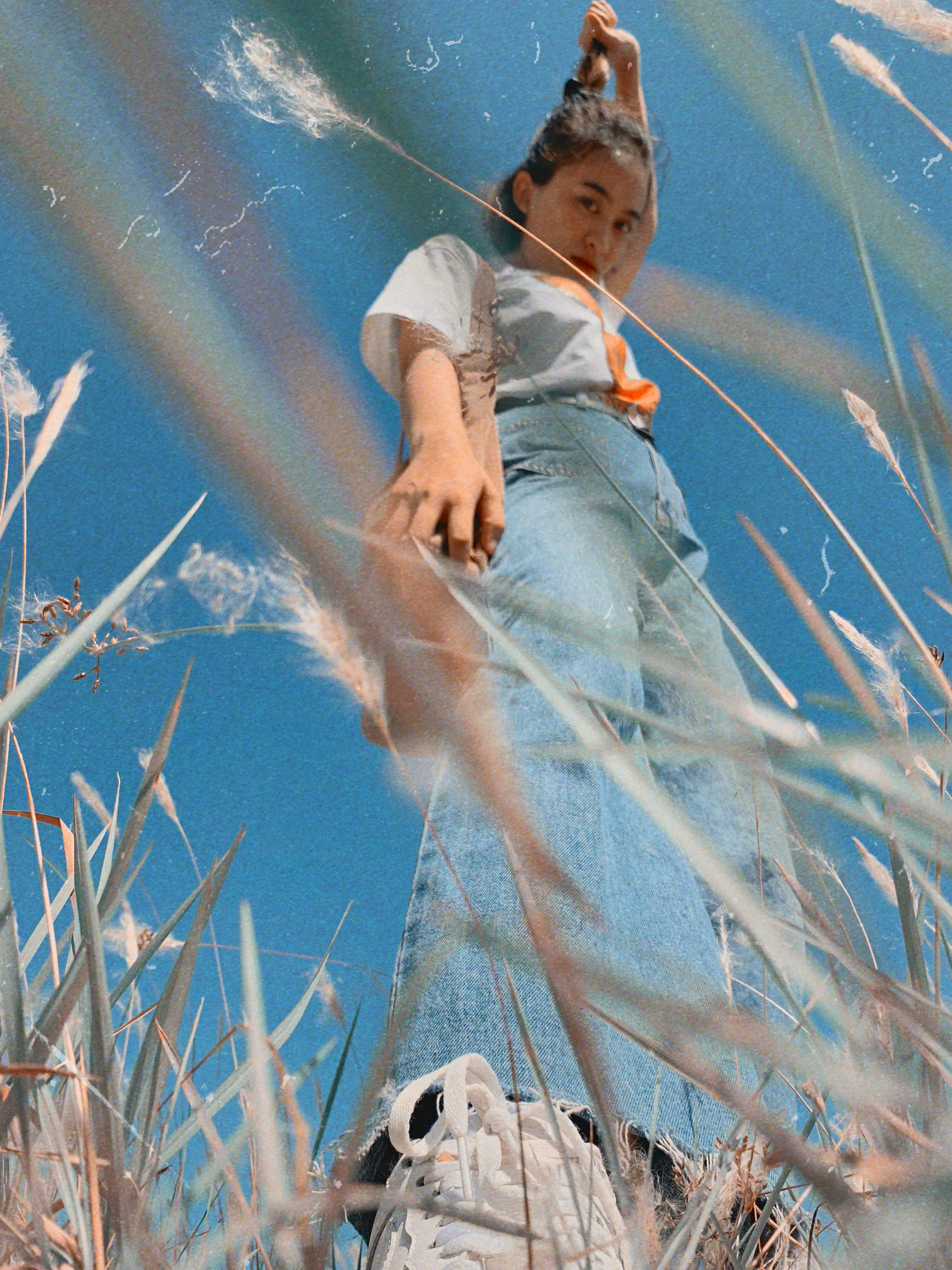 Low angle photo of a fashionable young adult outdoors with a vivid blue sky backdrop.