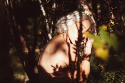 Free Nude Woman Sitting in Forest Illuminated by Sunlight Stock Photo