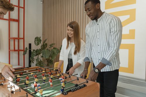 Free A diverse group of adults playing foosball together in a modern indoor setting. Stock Photo