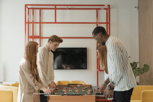 Free A diverse group of young adults playing foosball together in a cozy indoor setting. Stock Photo