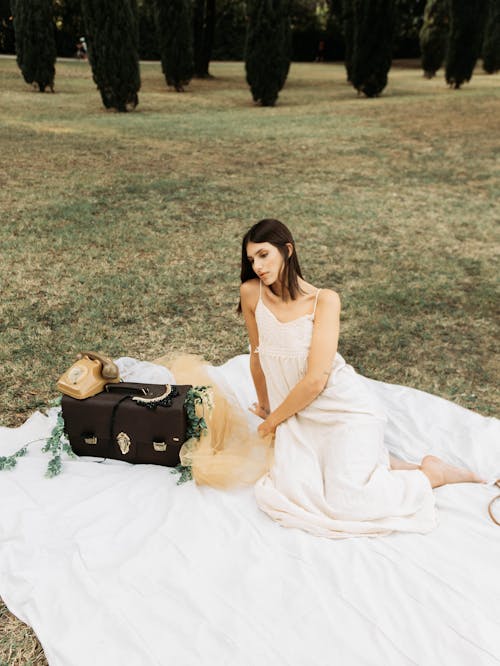 Romantic woman in white dress resting in park