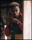 Focused black man touching lapel in grunge room
