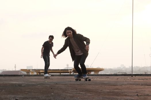 Two young skateboarders enjoying a rooftop ride during sunset, embracing urban adventure.