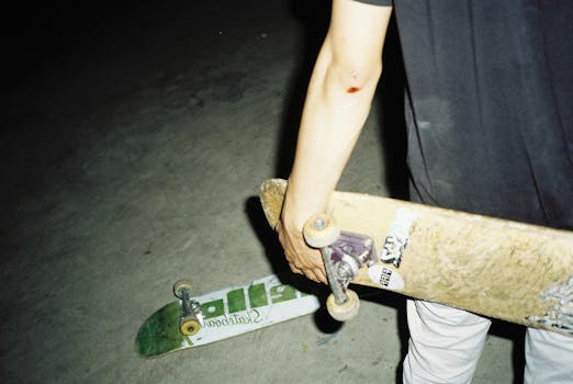 特写镜头中，夜间滑板者手持滑板，展现城市街头文化