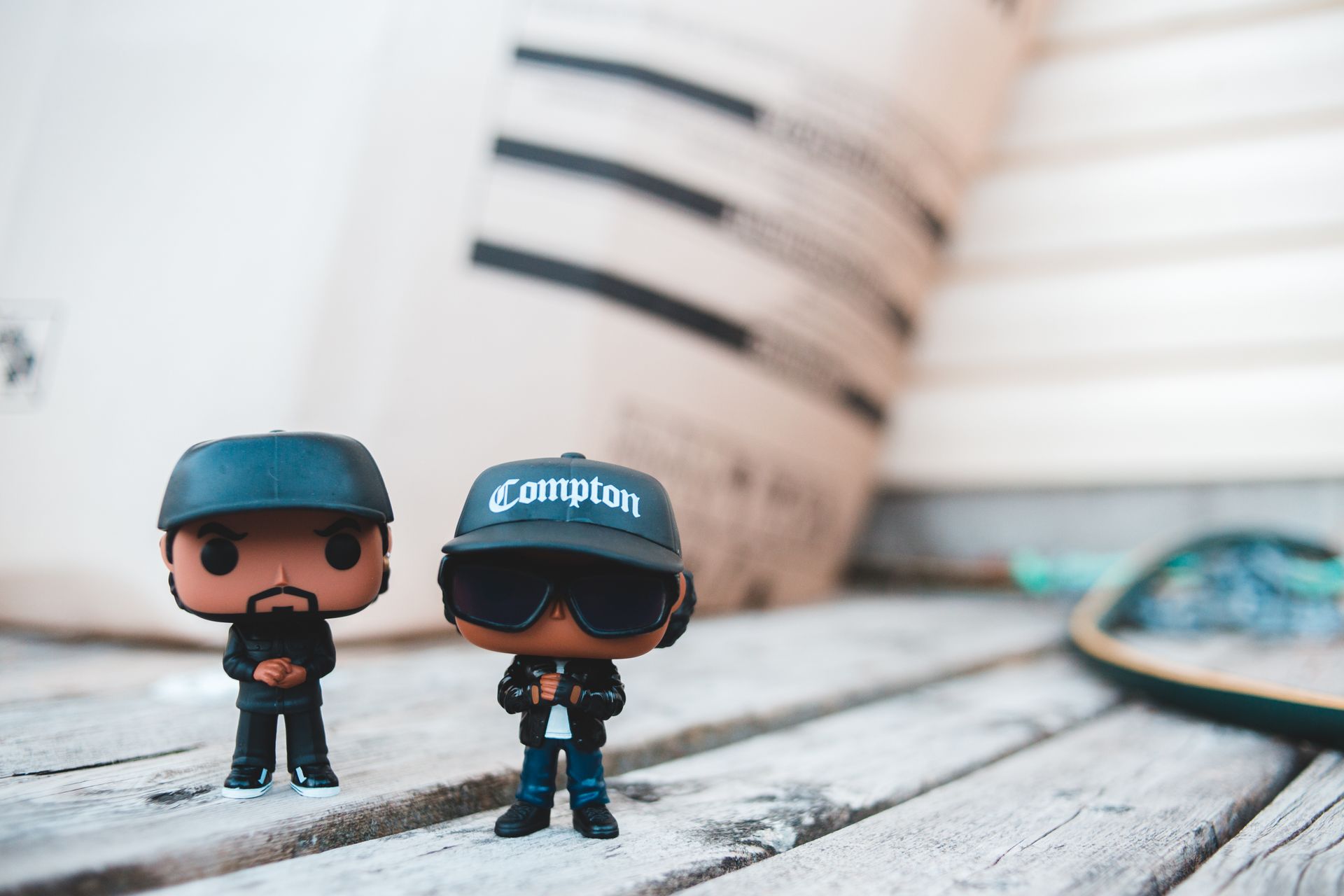 Trendy rappers toys in stylish outfits and caps placed on wooden table on sunny day