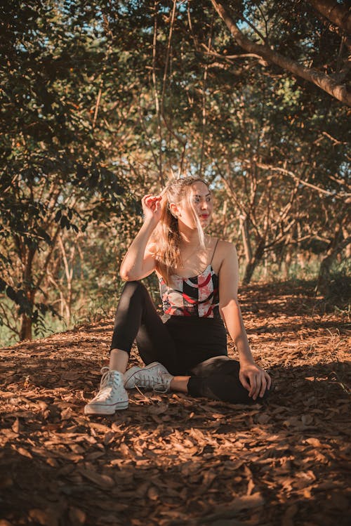 Woman in the Forest Sitting on Ground Covered with Dried Leaves 