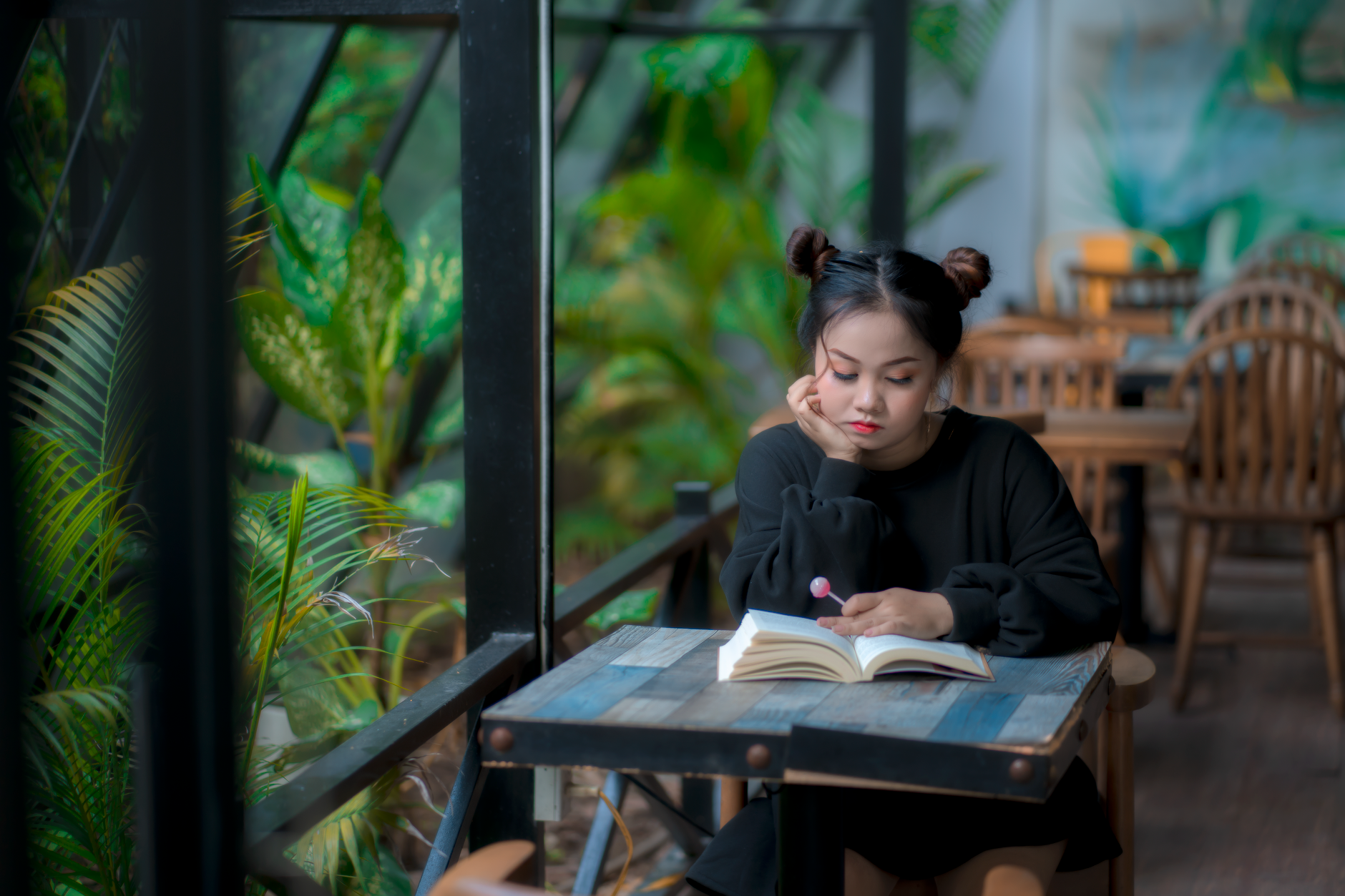 Một người phụ nữ Châu Á đang say sưa đọc sách trong không gian quán cà phê ấm cúng.