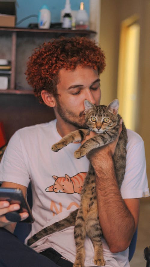 Free Man Holding his Cat and Using his Smart Phone  Stock Photo