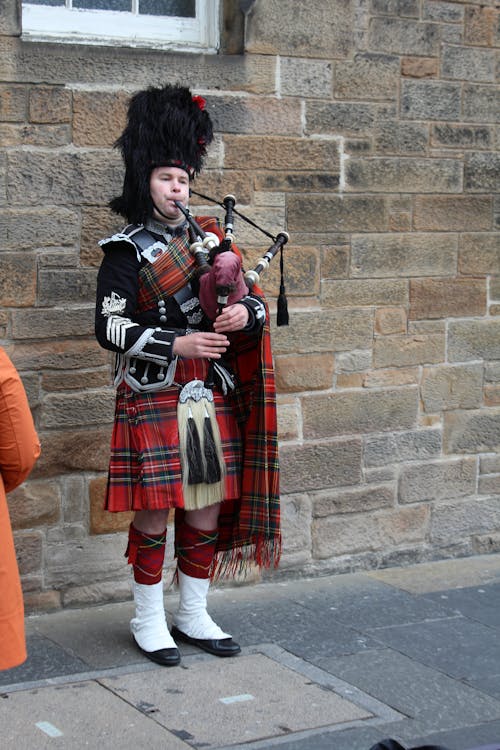 Man Wearing a Traditional Costume and Playing on Bagpipes