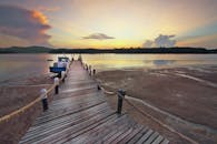 宁静的日落映照在宁静的河面上，可以看到木制码头和船只