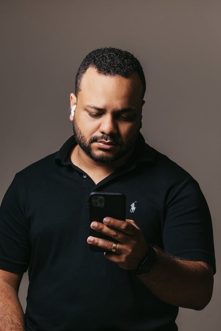 Young Black Man Standing And Using Smartphone