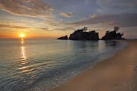 在幽静的海滩上，宁静的日出、温和的海浪和岩石营造出宁静的氛围