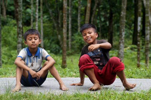 Free Two boys enjoying a day outdoors sitting on a path in a lush Indian forest. Stock Photo