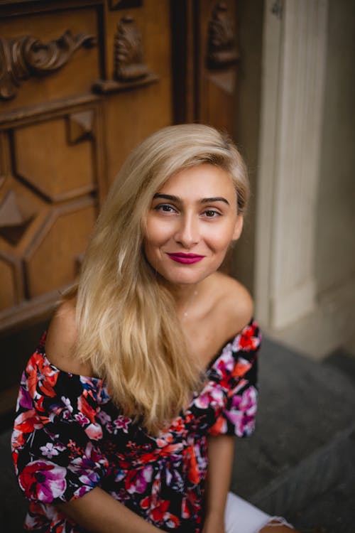 Woman with Blonde Hair Sitting on a Step while Smiling at Camera