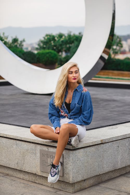 Woman in Blue Denim Jacket sitting on the Concrete Bench