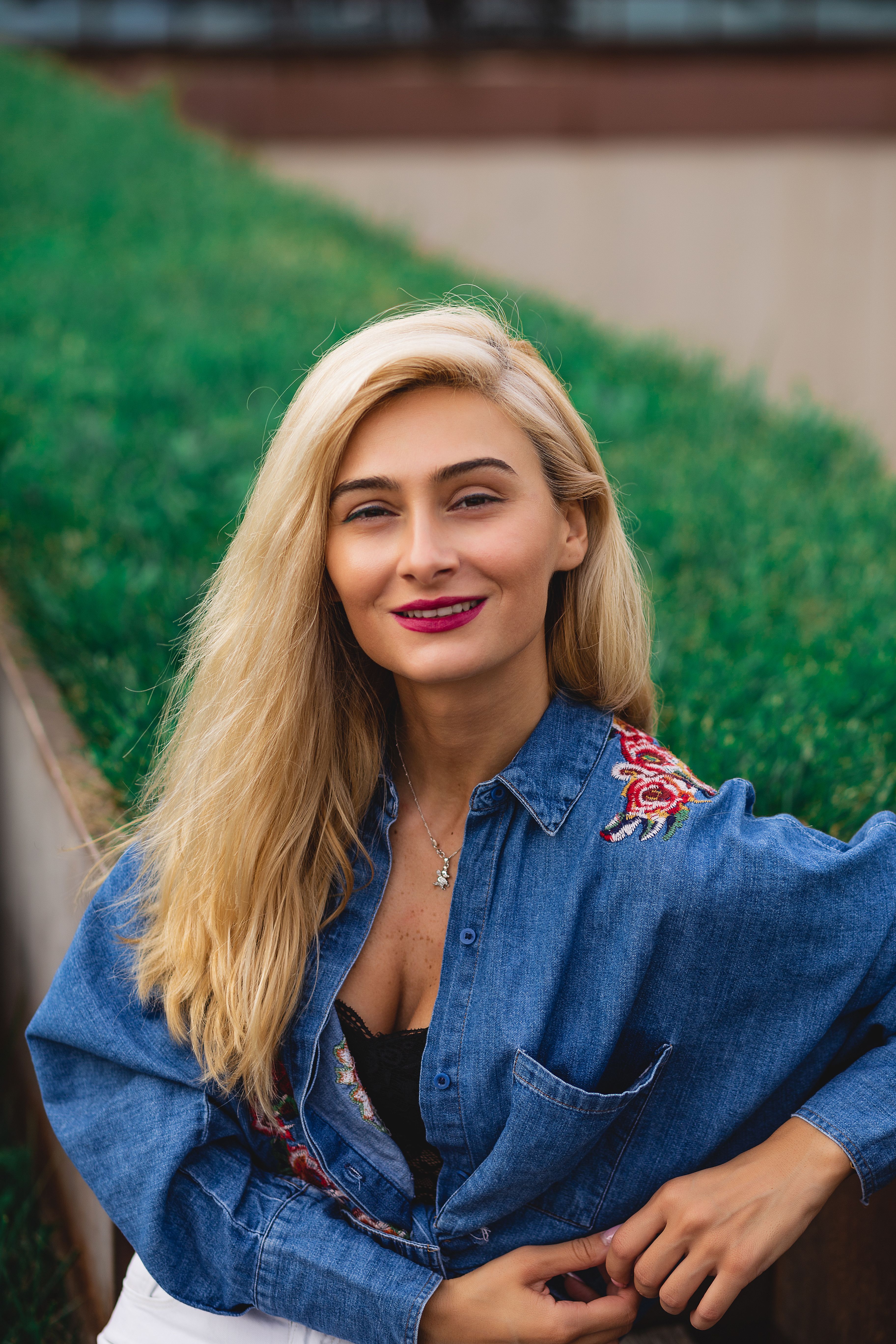 Woman in Blue Denim Jacket Standing on Green Grass Field · Free Stock Photo