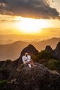 日落时分，一个人打扮成天使模样，长着翅膀，坐在一座岩石山上