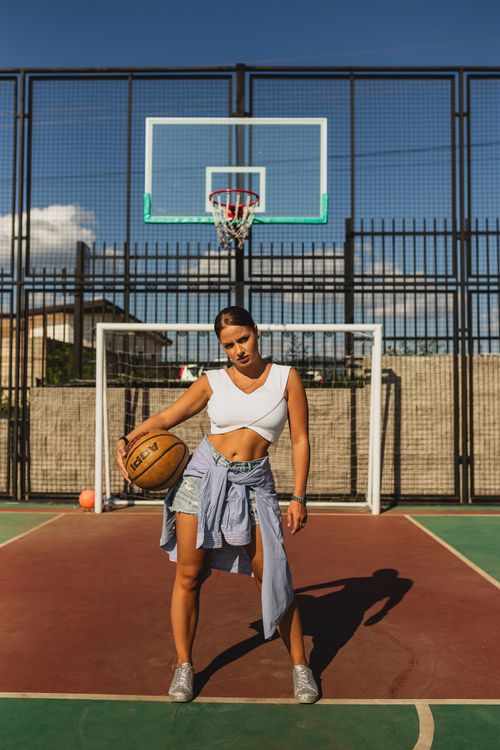 Free Stylish woman posing on a basketball court in sunny weather, showcasing sports fashion. Stock Photo