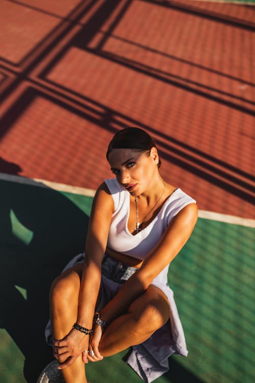 Free Woman in White Tank Top Posing on a Basketball Court Floor  Stock Photo
