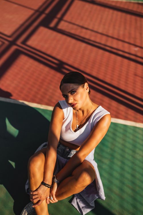 Free Stylish woman in denim shorts poses on a sunlit basketball court. Warm and vibrant outdoor setting. Stock Photo