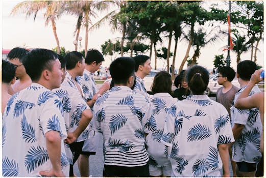 A group enjoying a tropical outdoor gathering in matching shirts, surrounded by palm trees and a coastal ambiance.