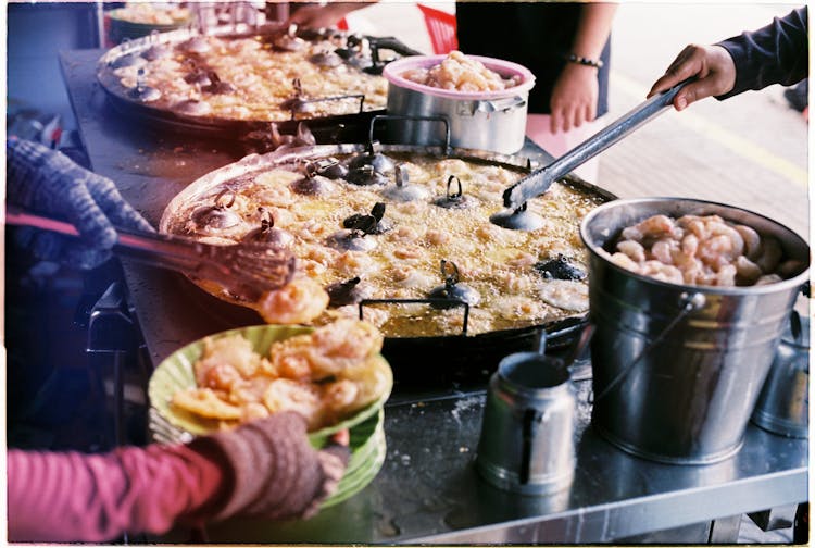 Cooks Frying Shrimps On Large Pans On The Street