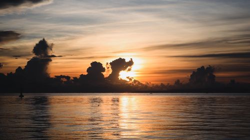 Free Tranquil sunset scene with dramatic clouds reflected over a still lake. Perfect for nature backdrops and wallpapers. Stock Photo