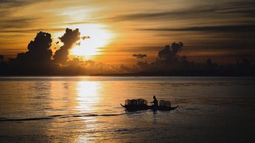 Silhouette of Person Sailing a Boat during Sunset