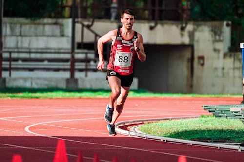 Full body of focused fit sportsman running on track during competition on stadium