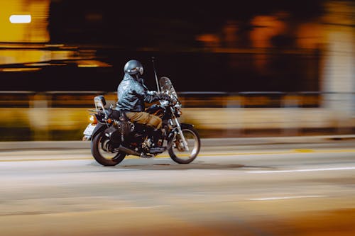Unrecognizable biker riding motorcycle at night