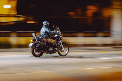 Free Faceless man in helmet riding motorbike on empty asphalt city road at night Stock Photo