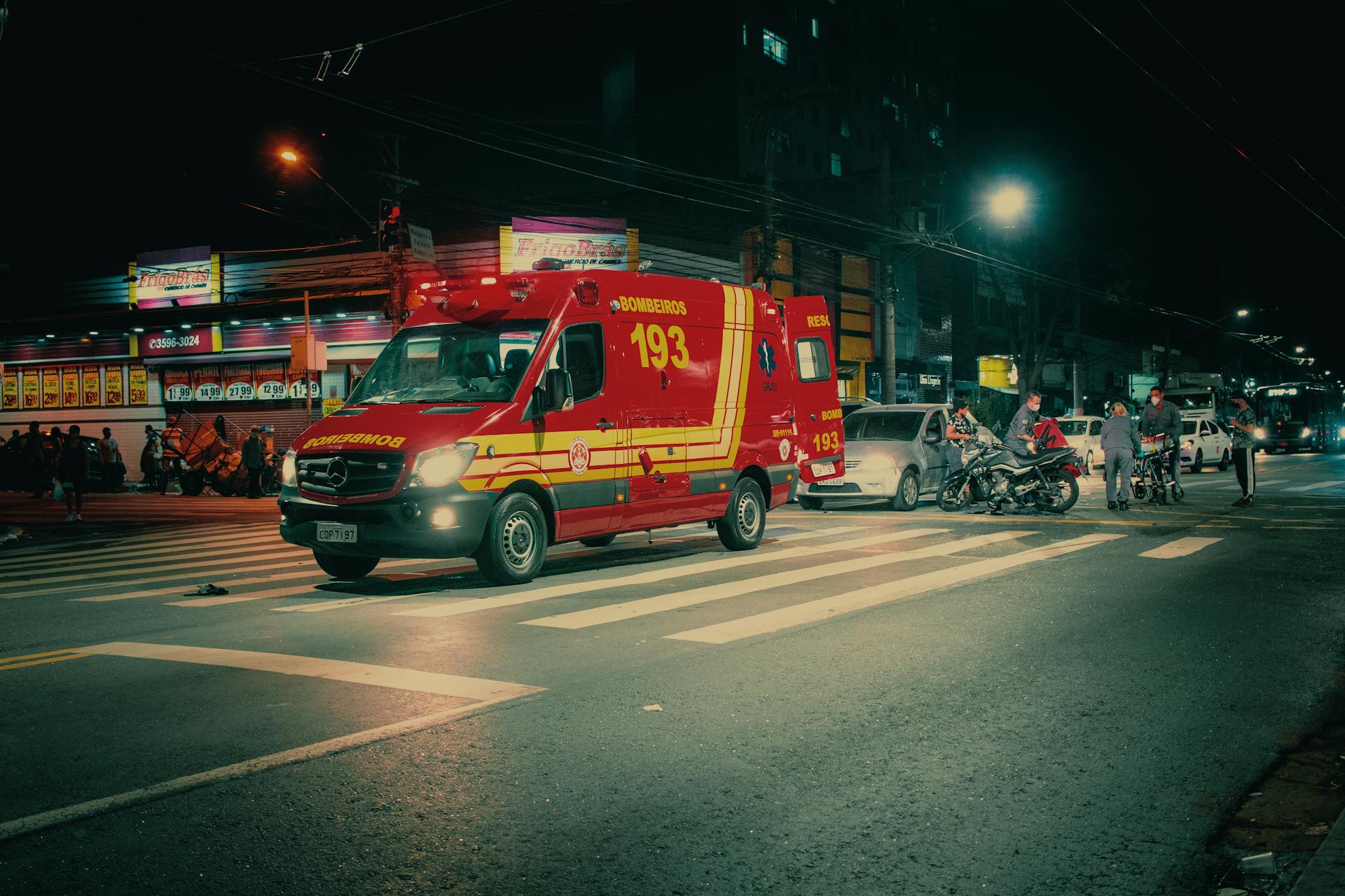 Red emergency transport near  car crash on illuminated night street in modern city