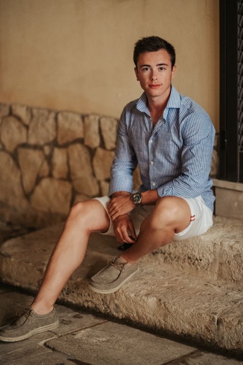 Free Full body of male in casual clothes sitting on stone stairs near building and looking at camera Stock Photo