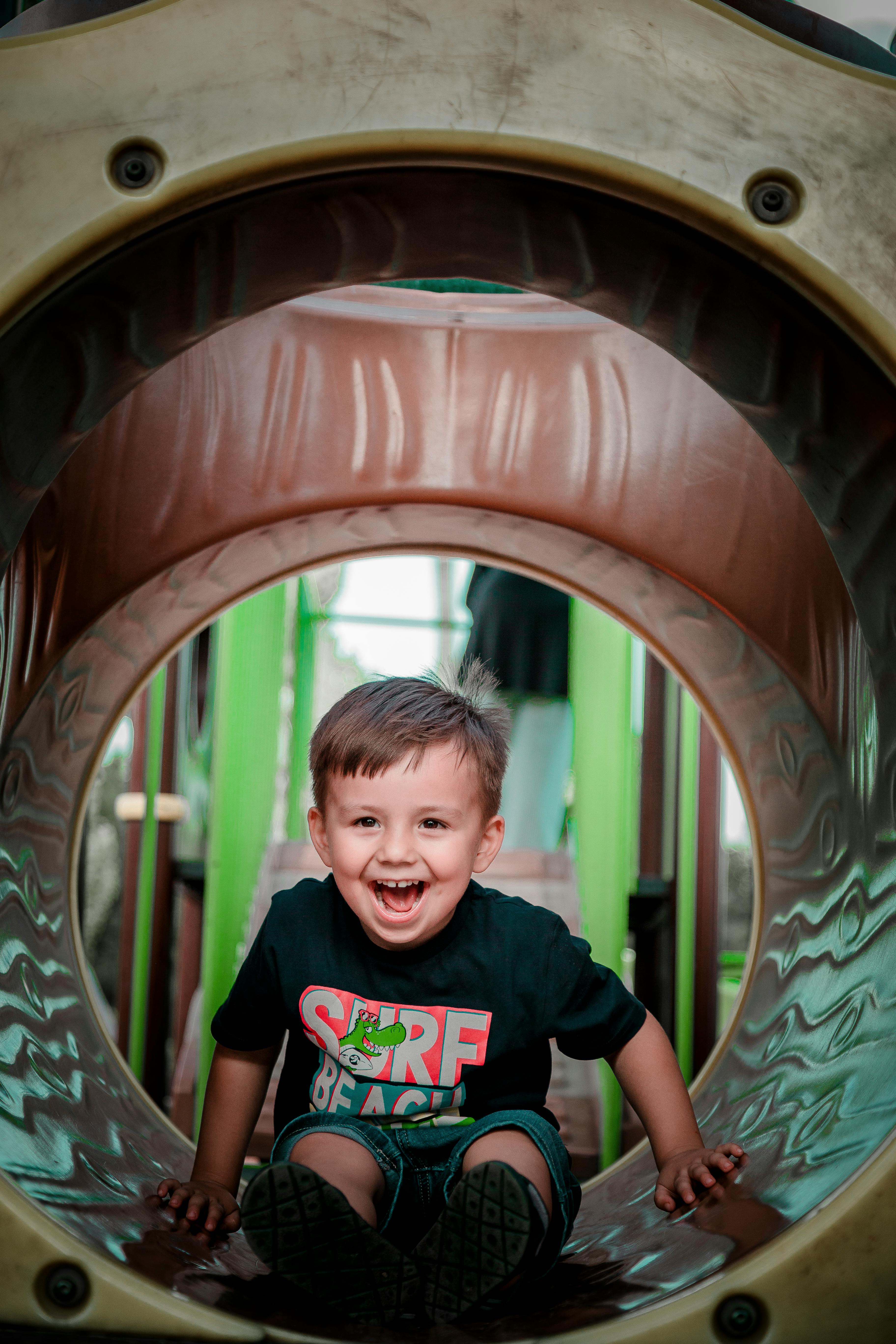 happy little boy sitting in a tube in an indoor playground