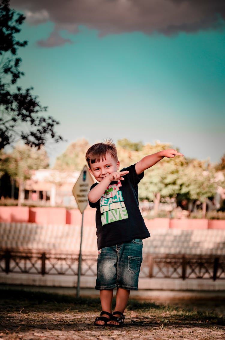 Smiling Boy Pointing His Hands To The Side 