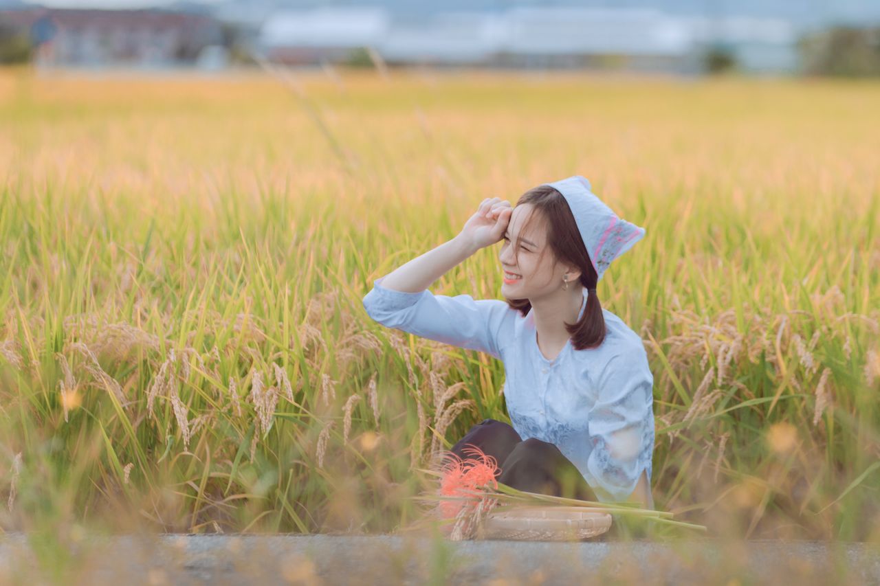 a smiling woman in a headscarf enjoys a sunny day in a lush rice field