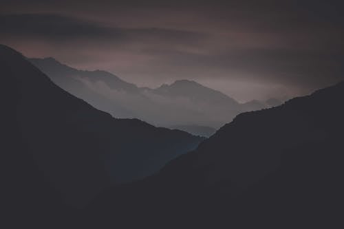 Free Gloomy landscape of dark mountains and gray sky with heavy clouds at night Stock Photo