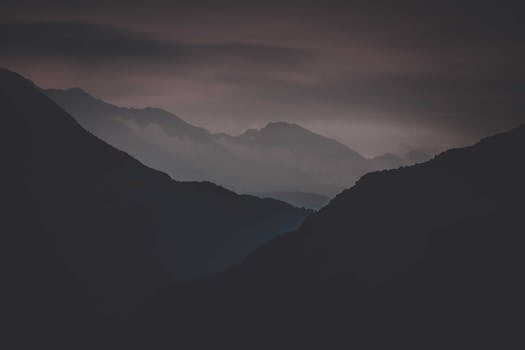 Gloomy landscape of dark mountains and gray sky with heavy clouds at night