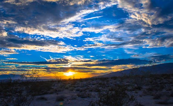 沙漠景观上，蔚蓝的天空和壮观的云层衬托出令人惊叹的日落