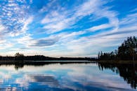 在充满活力的蓝天下，宁静的湖泊倒映着森林的影子