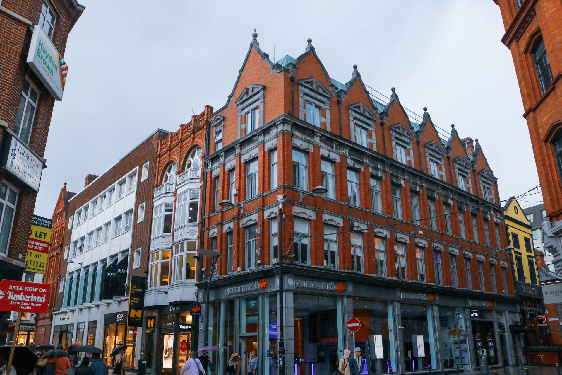 Vibrant urban street featuring historic red brick architecture and bustling pedestrians.