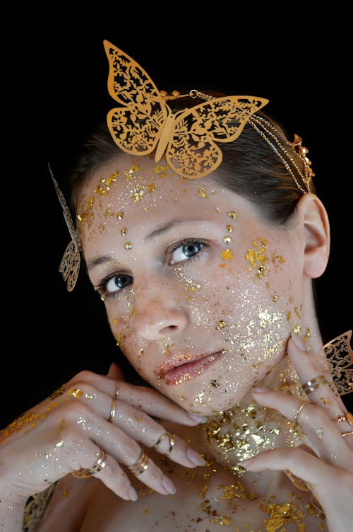 Woman with gold leaf makeup wearing butterfly headband in studio