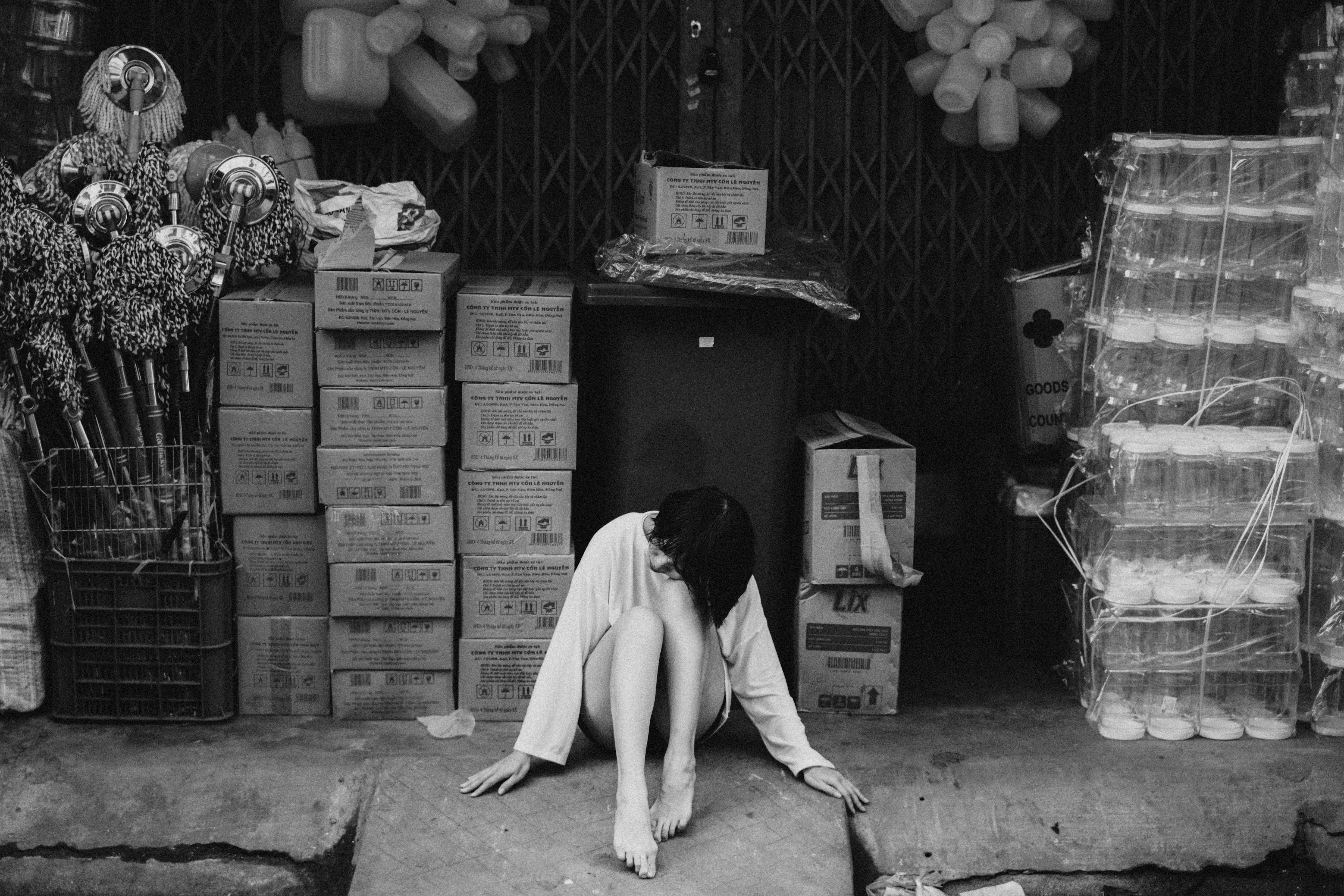 A thoughtful black and white street scene with a woman sitting in an industrial setting.