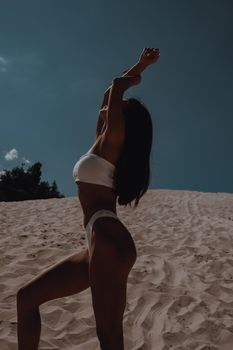 Side view of fit sensual female sunbathing on sandy beach of seashore in hot weather