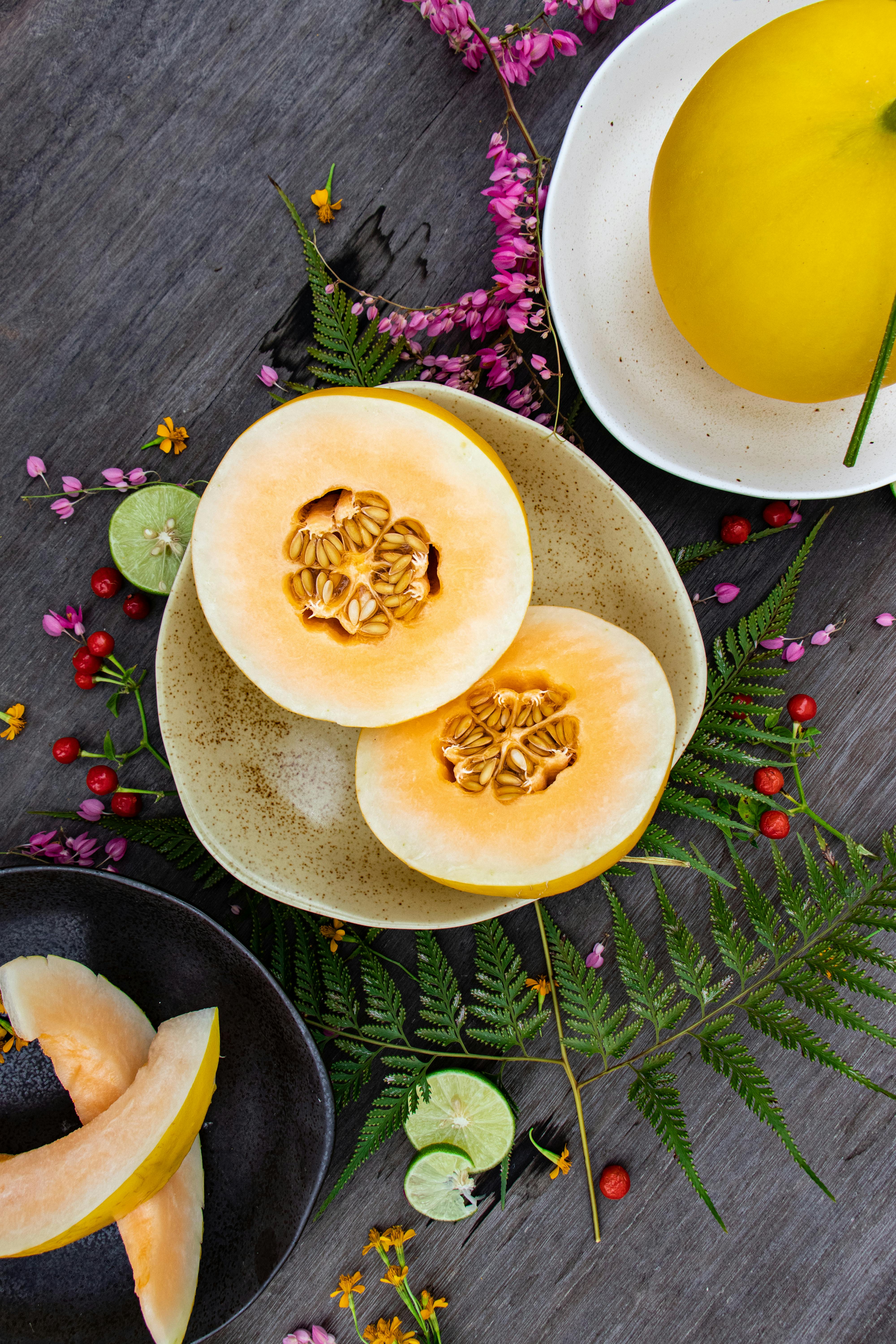 A vibrant flat lay of sliced melon with floral accents, showcasing freshness and summer vibes.