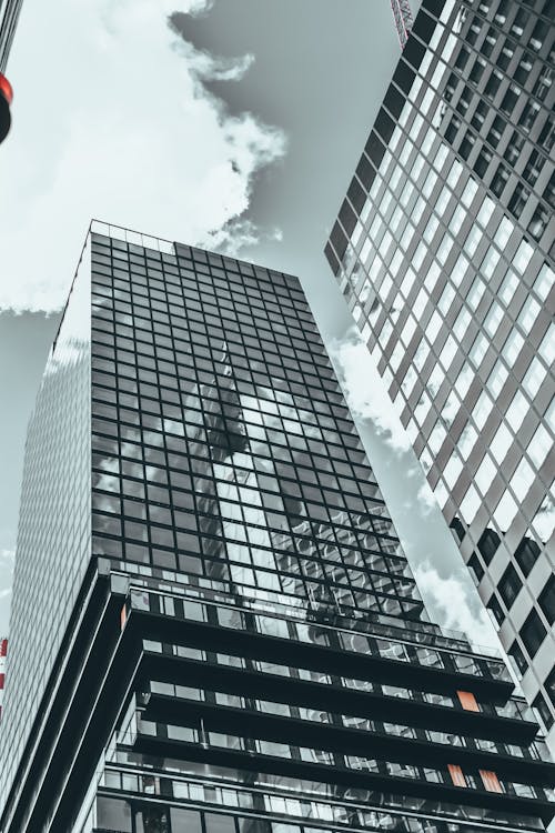 From below of modern multistory house facades with shiny walls under cloudy sky in city