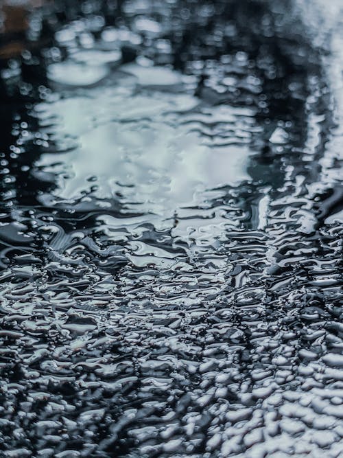 Abstract background of rippled lake with translucent water droplets in rainy weather in daylight